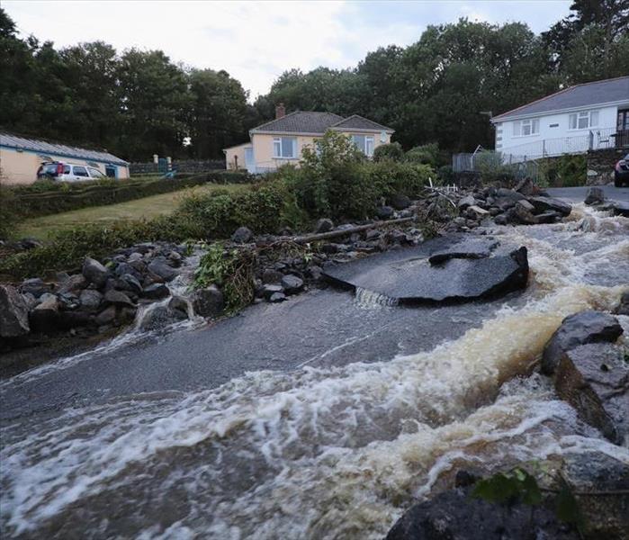water rushing down a rocky hill in front of houses